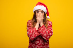 ann-share-price-Young woman wearing santa hat very scared and afraid hidden