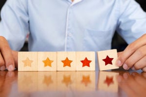 asx-200-asx-apt-afterpay-Businessman hand putting wooden five star shape on table.