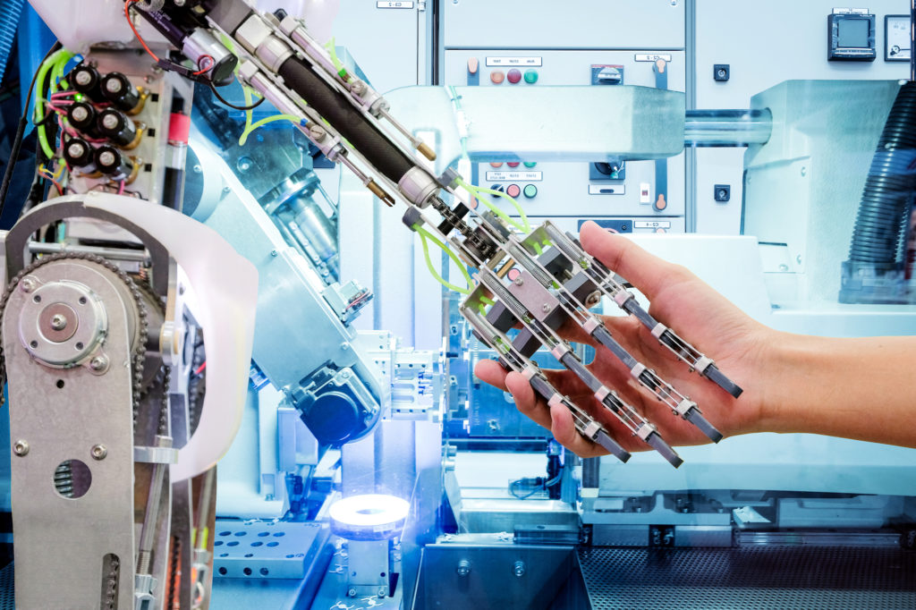 images shows a computer/robot shaking hands with a human in a lab