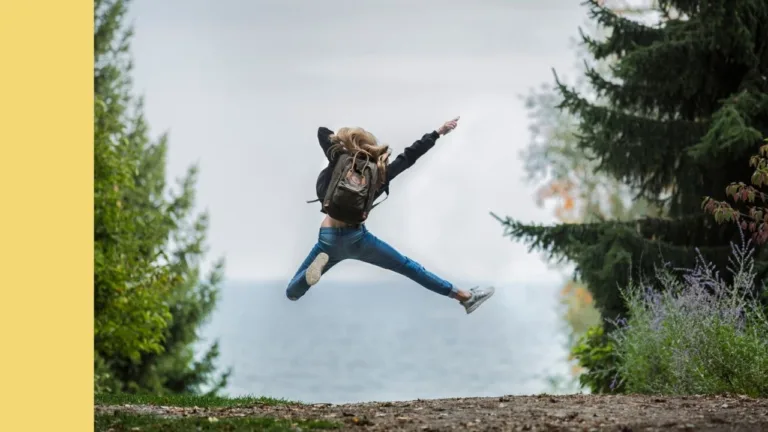 hiker jumping for joy on a dirt trail in the forrest