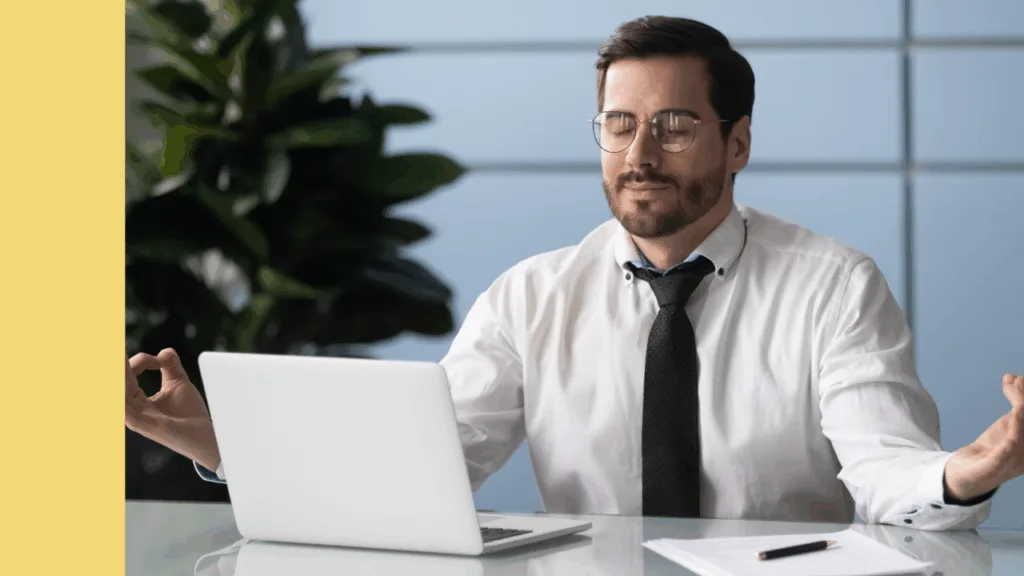 Professional working sitting at desk in front of laptop meditates calmly
