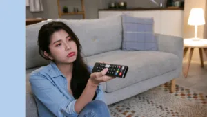 girl looks sad as she points her tv remote at a tv