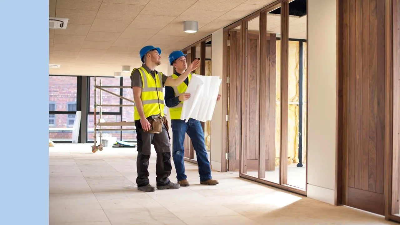 Two builders look at plans and discuss fitout construction