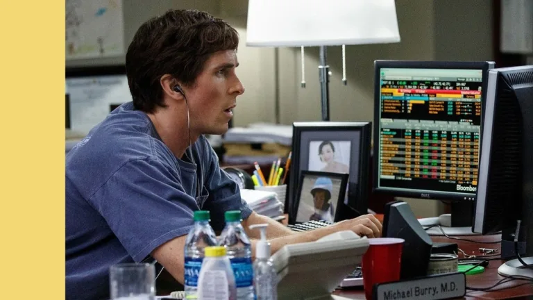 Actor Christian Bale potraying investor Michael Burry intensely looks at a computer screen showing stock market data