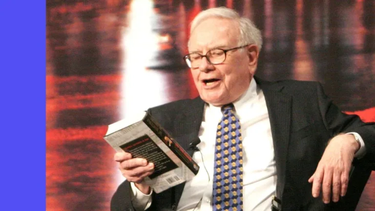 Warren Buffett relaxes in a chair, looking down at a book to read