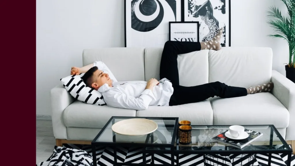 Man lies across couch looking exhausted