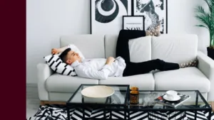 Man lies across couch looking exhausted