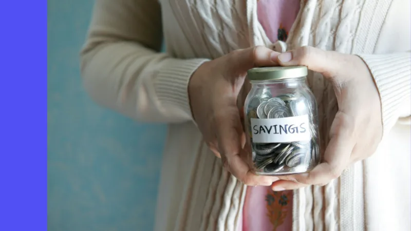 Person holding a jar of coins labelled savings