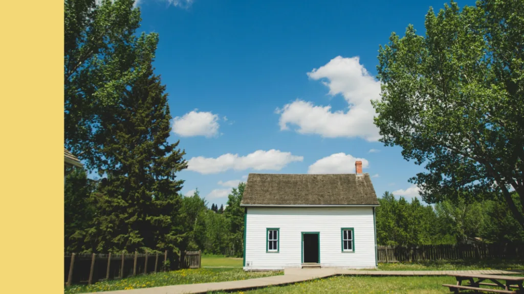 Small house with a lawn and trees under a blue sky
