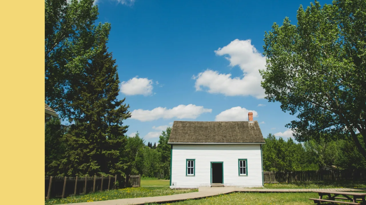 Small house with a lawn and trees under a blue sky